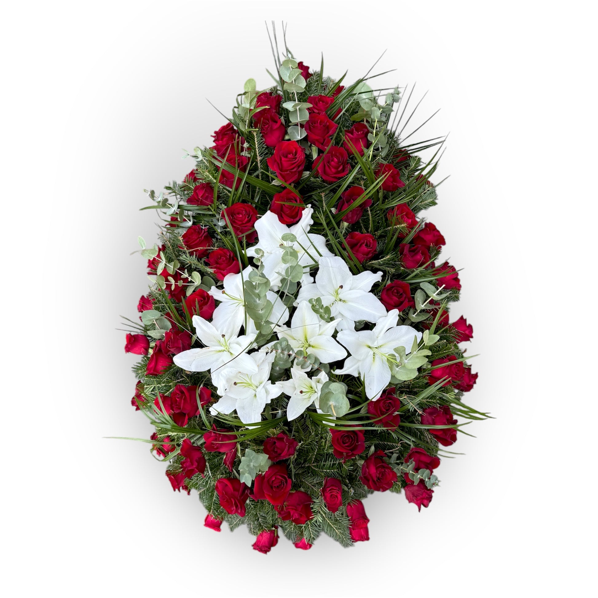 Coroană funerară realizată din trandafiri roșii și din gypsophila și crini albi și ornată cu plante decorative: frunze de eucalipt și Parlor Palme.